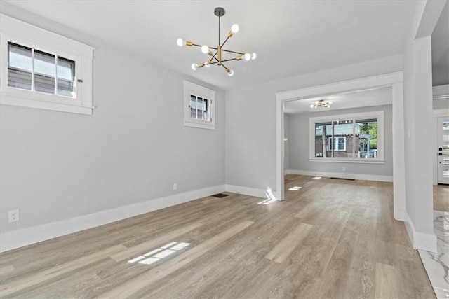 unfurnished dining area with a chandelier, light wood-type flooring, and baseboards