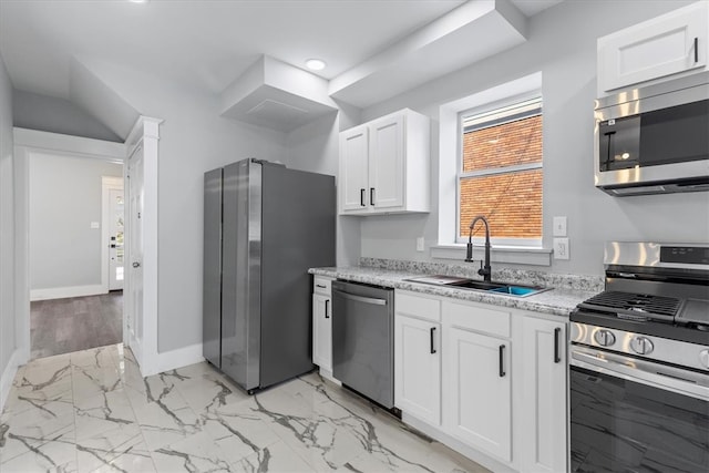 kitchen featuring sink, appliances with stainless steel finishes, light stone countertops, light hardwood / wood-style floors, and white cabinets