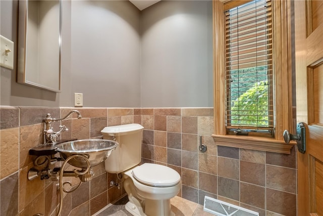 bathroom with tile walls, tile patterned flooring, sink, and toilet