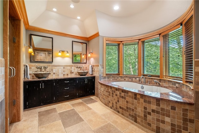 bathroom featuring backsplash, tiled tub, vanity, tile patterned flooring, and a tray ceiling