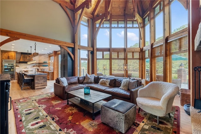 living room with high vaulted ceiling, light hardwood / wood-style flooring, and beamed ceiling