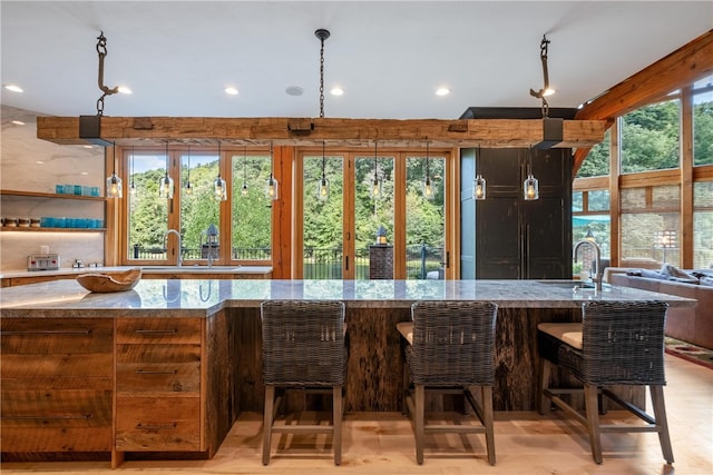 kitchen with a kitchen breakfast bar, sink, pendant lighting, and light stone counters