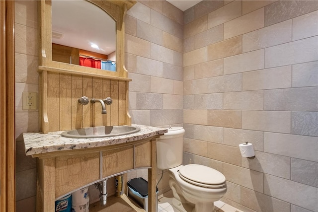 bathroom with sink, toilet, tile patterned flooring, and tile walls