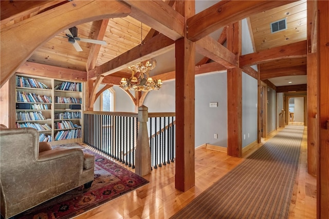 interior space featuring ceiling fan with notable chandelier, light hardwood / wood-style floors, wooden ceiling, and lofted ceiling with beams