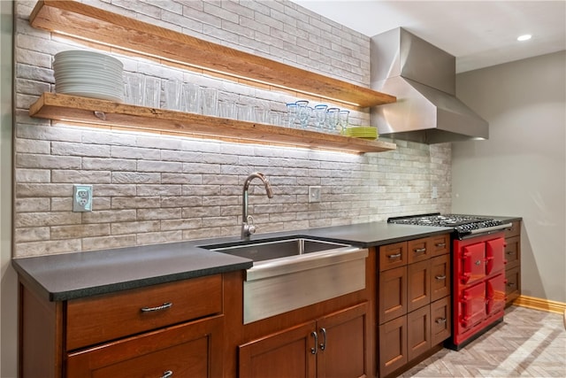 kitchen featuring backsplash, sink, wall chimney range hood, and range