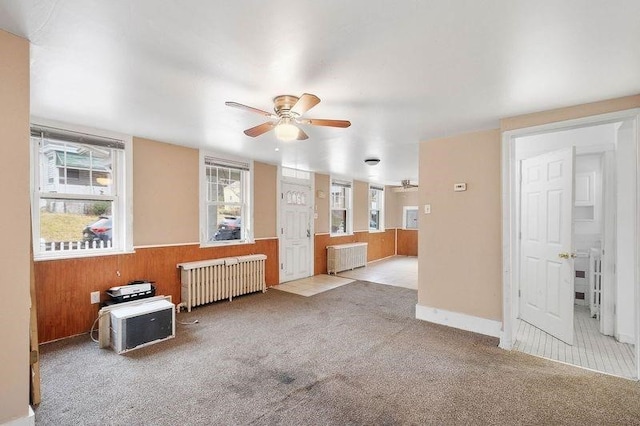 empty room with ceiling fan, light colored carpet, and radiator