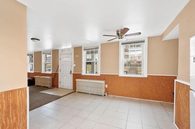 unfurnished room featuring radiator heating unit, ceiling fan, and light tile patterned floors