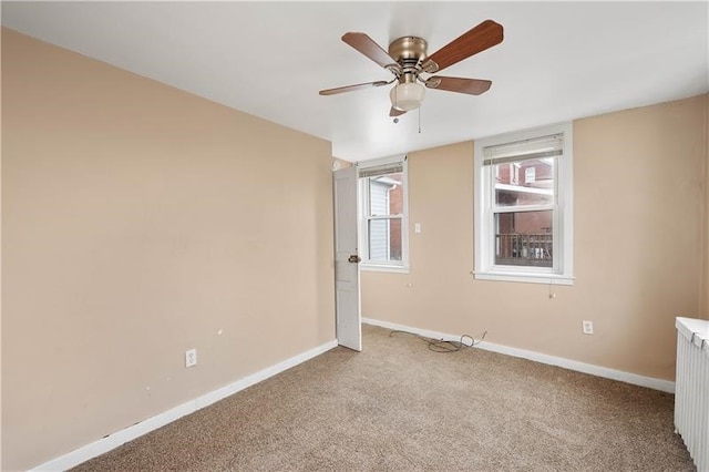 spare room with ceiling fan, light colored carpet, and radiator heating unit