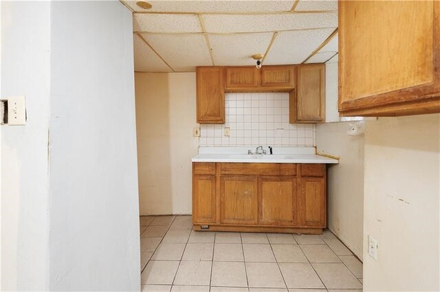 kitchen featuring light tile patterned floors, sink, tasteful backsplash, and a paneled ceiling