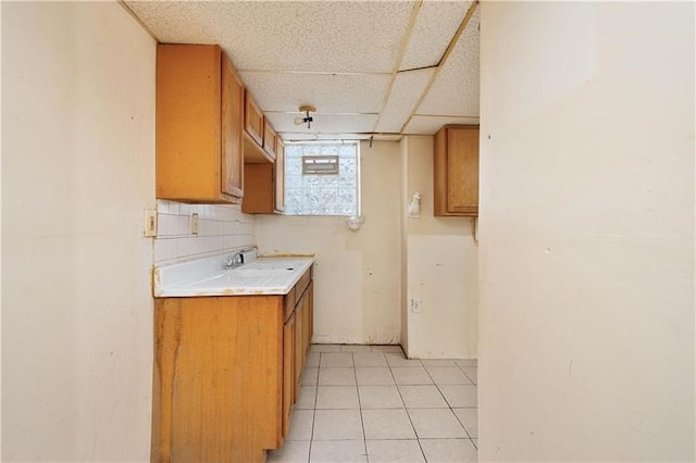 kitchen featuring a drop ceiling, decorative backsplash, and light tile patterned floors