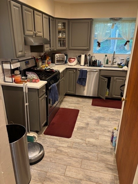 kitchen with sink, stainless steel appliances, gray cabinets, and tasteful backsplash