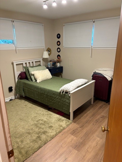 bedroom featuring hardwood / wood-style flooring and track lighting