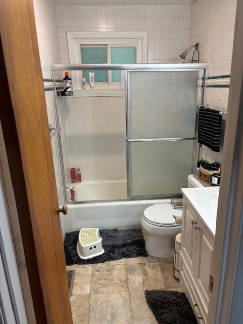 full bathroom featuring tile patterned floors, vanity, shower / bath combination with glass door, and toilet