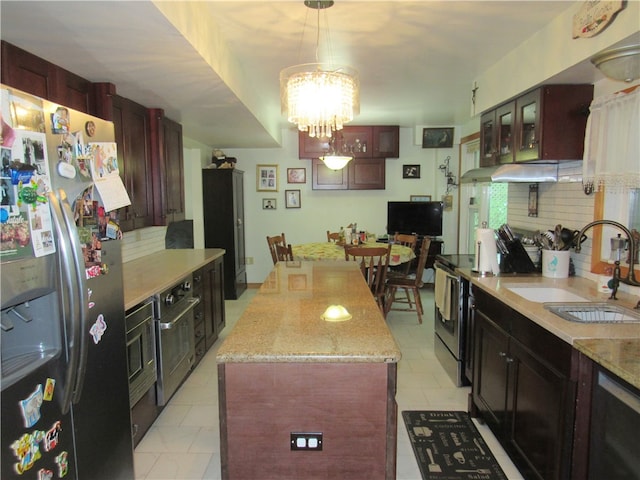 kitchen with hanging light fixtures, stainless steel fridge, sink, backsplash, and a chandelier