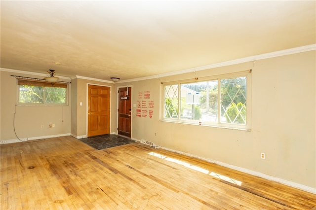 unfurnished room with plenty of natural light, crown molding, baseboard heating, and hardwood / wood-style flooring