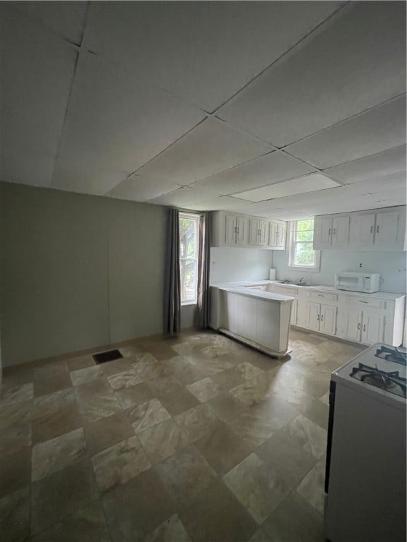 kitchen with plenty of natural light, white cabinetry, a paneled ceiling, and white appliances