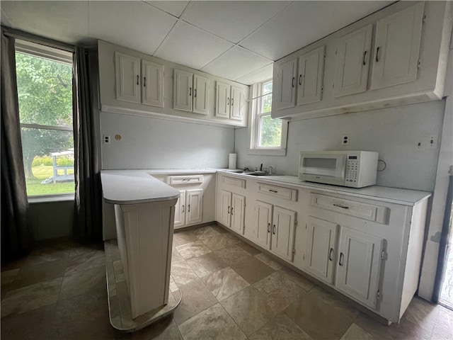 kitchen with kitchen peninsula, white cabinetry, and light tile patterned flooring