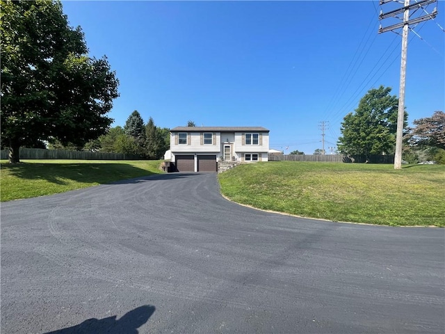 split foyer home with a garage, aphalt driveway, a front lawn, and fence