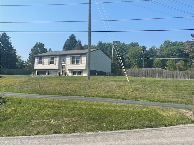 raised ranch with a front lawn and fence