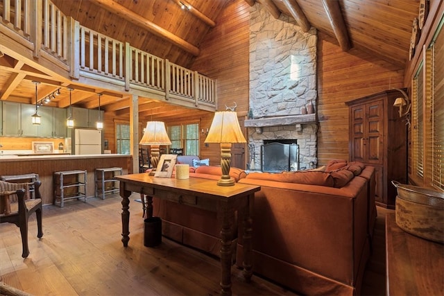 living room with a fireplace, high vaulted ceiling, beamed ceiling, and light wood-type flooring