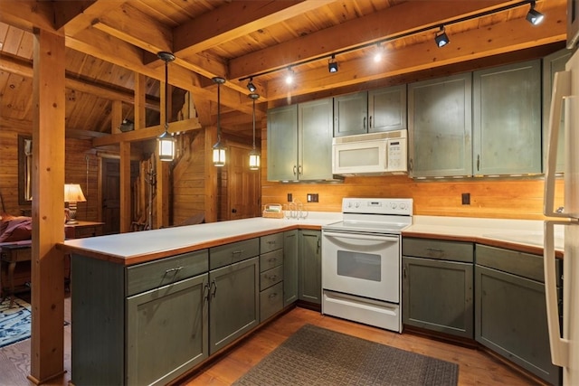 kitchen featuring white appliances, wooden walls, light wood-type flooring, and hanging light fixtures