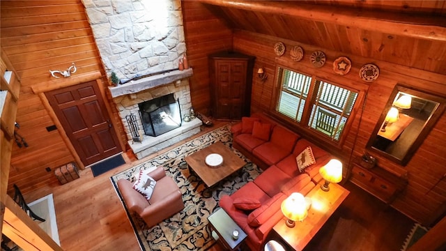 living room featuring a fireplace, wooden walls, wood-type flooring, vaulted ceiling, and wooden ceiling