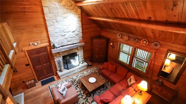 living room with hardwood / wood-style floors, a stone fireplace, wooden ceiling, lofted ceiling with beams, and wooden walls