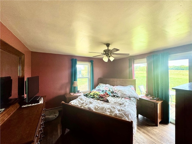 bedroom with light hardwood / wood-style floors, access to outside, and ceiling fan