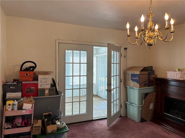 doorway with a notable chandelier, a fireplace, and carpet floors