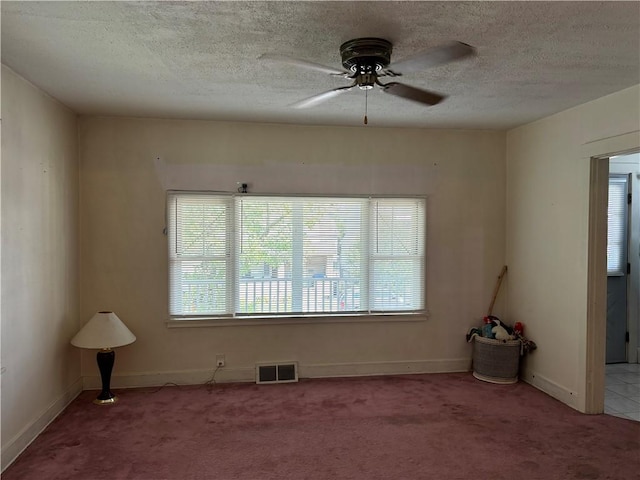 spare room featuring visible vents, a textured ceiling, ceiling fan, and carpet floors