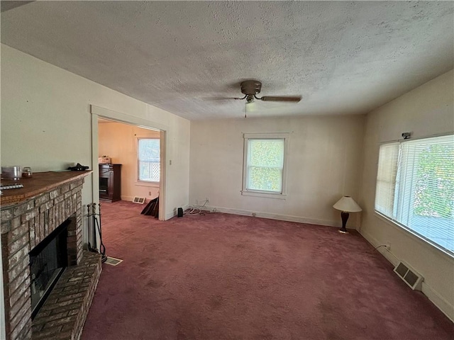 unfurnished living room featuring visible vents, a textured ceiling, carpet, baseboards, and a brick fireplace