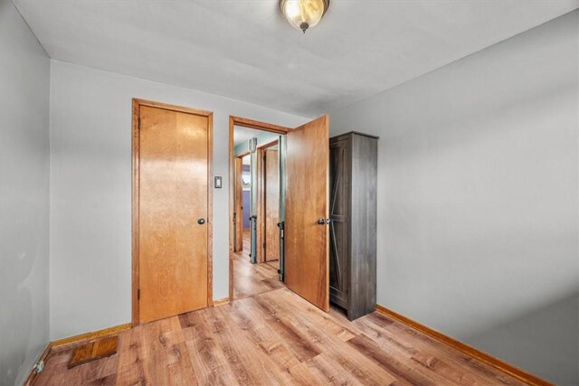 unfurnished bedroom with light wood-type flooring and a closet