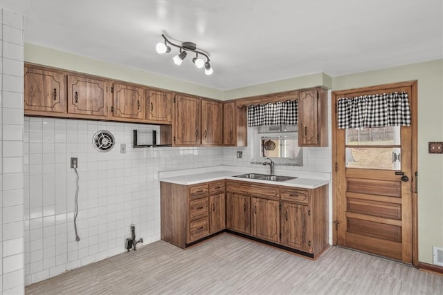 kitchen featuring tasteful backsplash, tile walls, light tile patterned floors, sink, and rail lighting