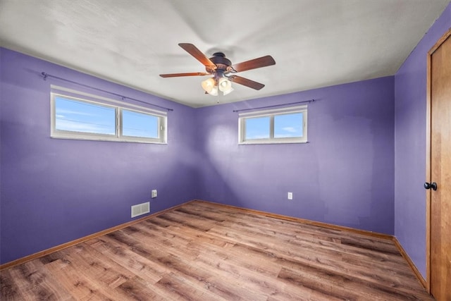 empty room featuring plenty of natural light, ceiling fan, and hardwood / wood-style flooring