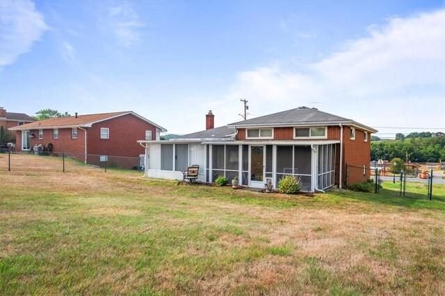 back of property featuring a yard and a sunroom