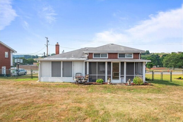 rear view of house with a sunroom and a lawn