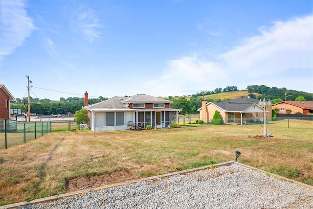 back of property with a sunroom and a yard