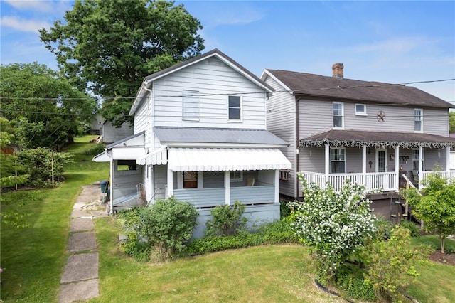 rear view of house with a lawn and a porch