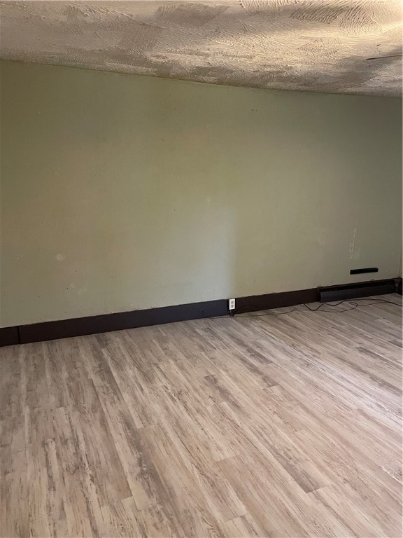 unfurnished room featuring light hardwood / wood-style floors and a textured ceiling