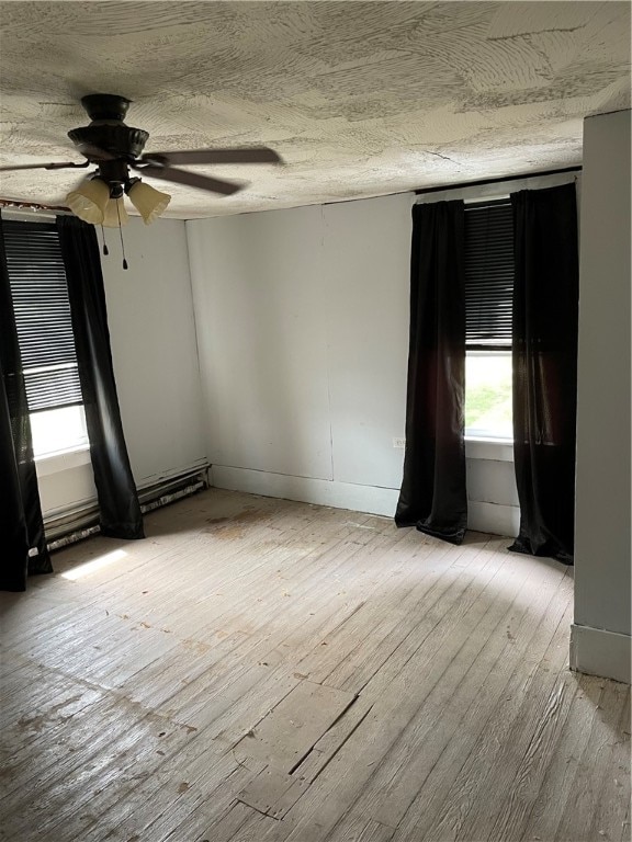 spare room with ceiling fan, light wood-type flooring, and a textured ceiling