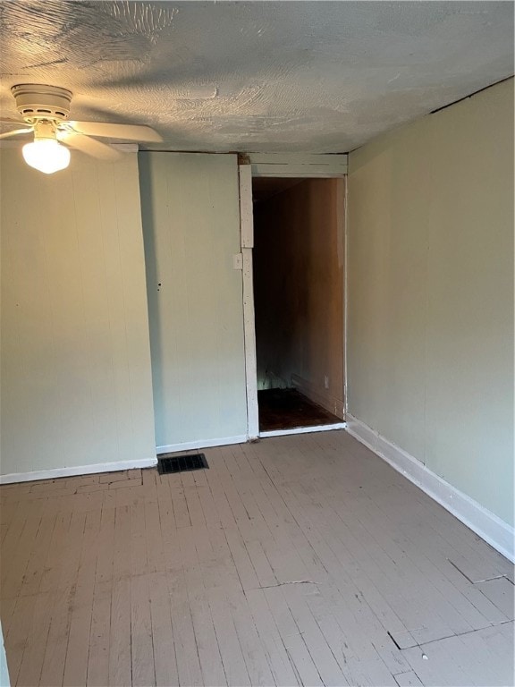 unfurnished room with a textured ceiling, ceiling fan, and hardwood / wood-style flooring