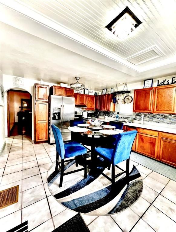 201 Esther Ave, New Kensington, PA 15068 - kitchen featuring stainless steel fridge with ice dispenser, light tile patterned floors, arched walkways, and decorative backsplash