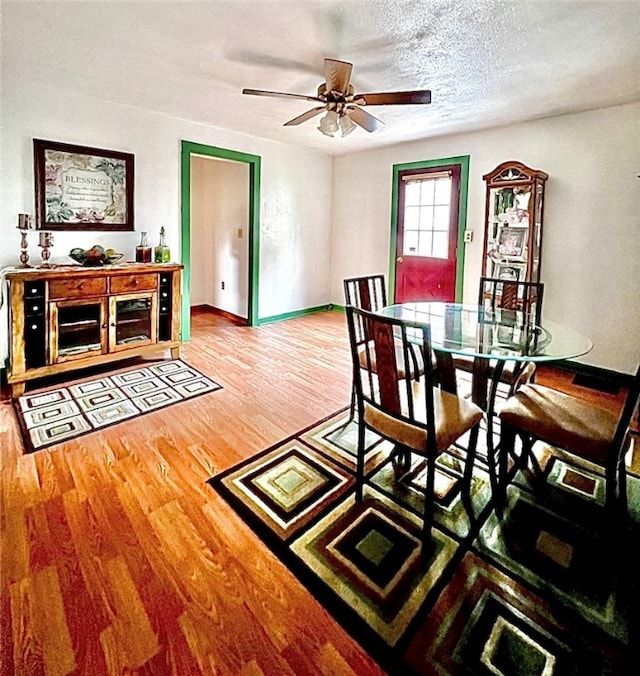 dining area with hardwood / wood-style floors, a textured ceiling, and ceiling fan