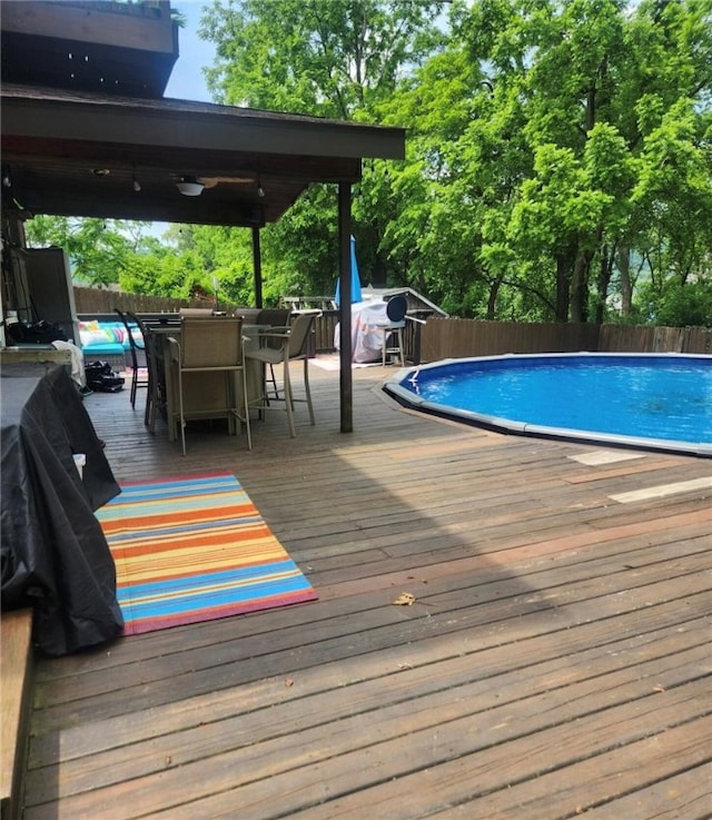 view of swimming pool with outdoor dining space, fence, a wooden deck, and a fenced in pool