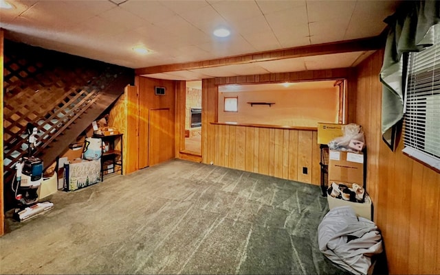 bonus room with beam ceiling, wooden walls, and carpet