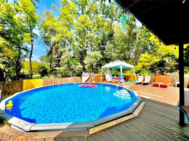 view of swimming pool featuring a deck, a gazebo, a fenced backyard, and a fenced in pool