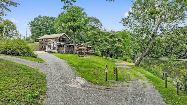 view of front of property featuring a front yard, a water view, and an outbuilding