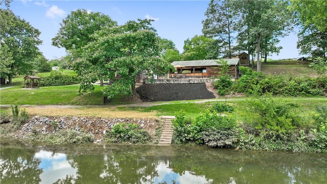 back of property with a lawn, a gazebo, and a water view