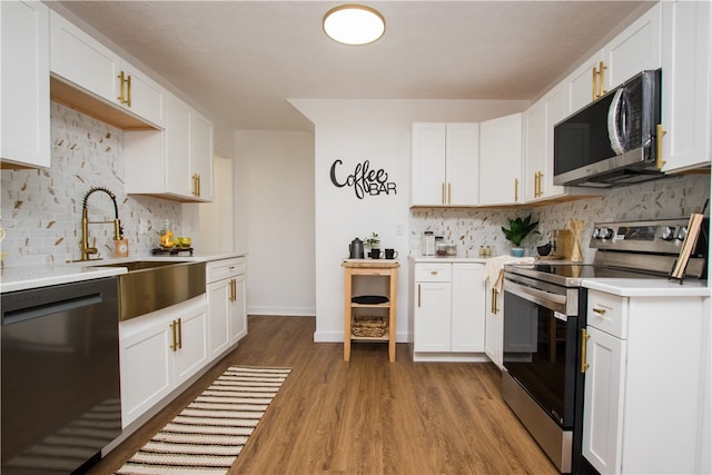 kitchen featuring light wood-type flooring, backsplash, stainless steel appliances, and white cabinets