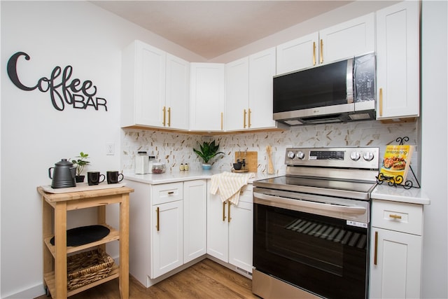 kitchen featuring white cabinetry, backsplash, appliances with stainless steel finishes, and light hardwood / wood-style floors